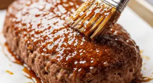 Brushing brown sugar glaze over Wagyu meatloaf