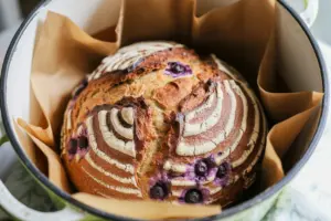 Golden Lemon Blueberry Sourdough Bread in a hot white Dutch oven