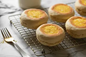 golden cornmeal-dusted english muffins on a wire rack