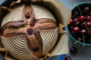 Golden loaf of chocolate cherry sourdough baking in cast-iron Dutch oven,