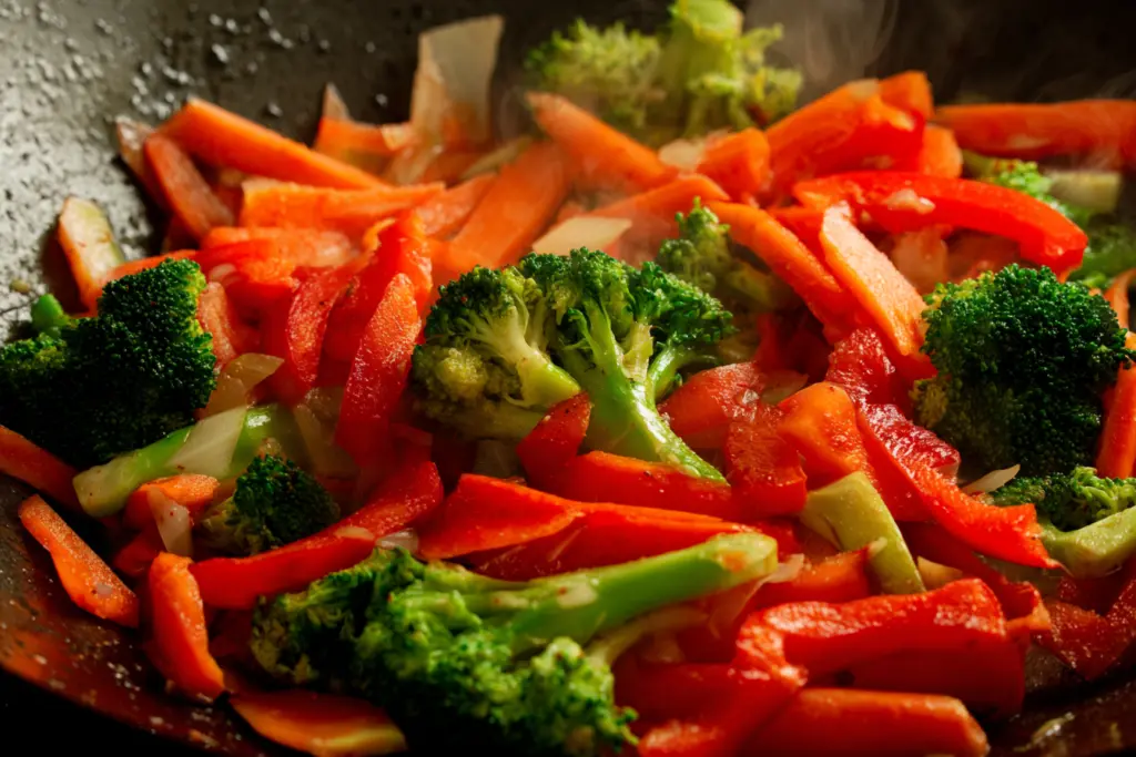 adding vegetables to chicken stir fry